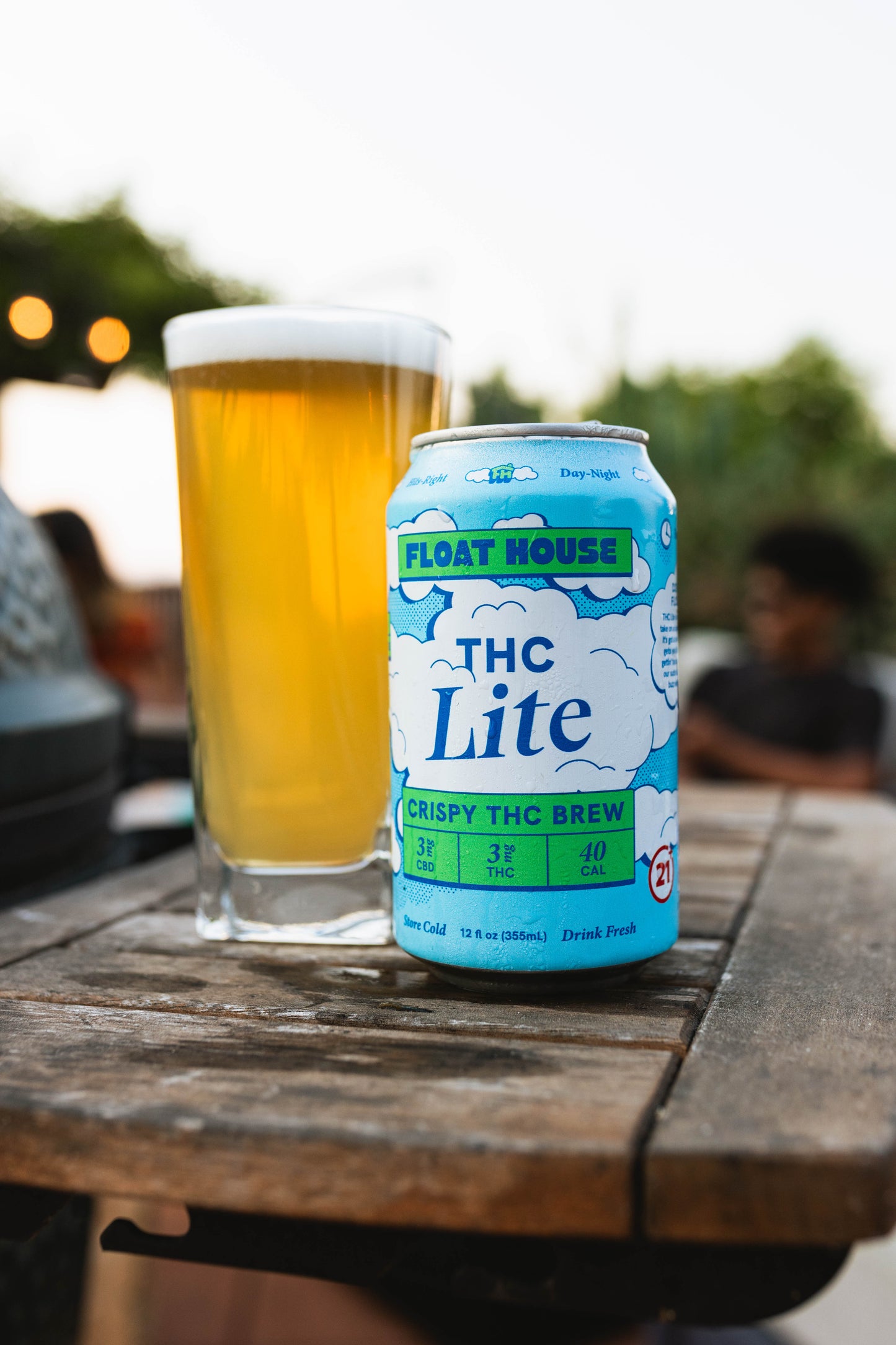 Can of THC Lite brew on a wooden table with a blurred outdoor background