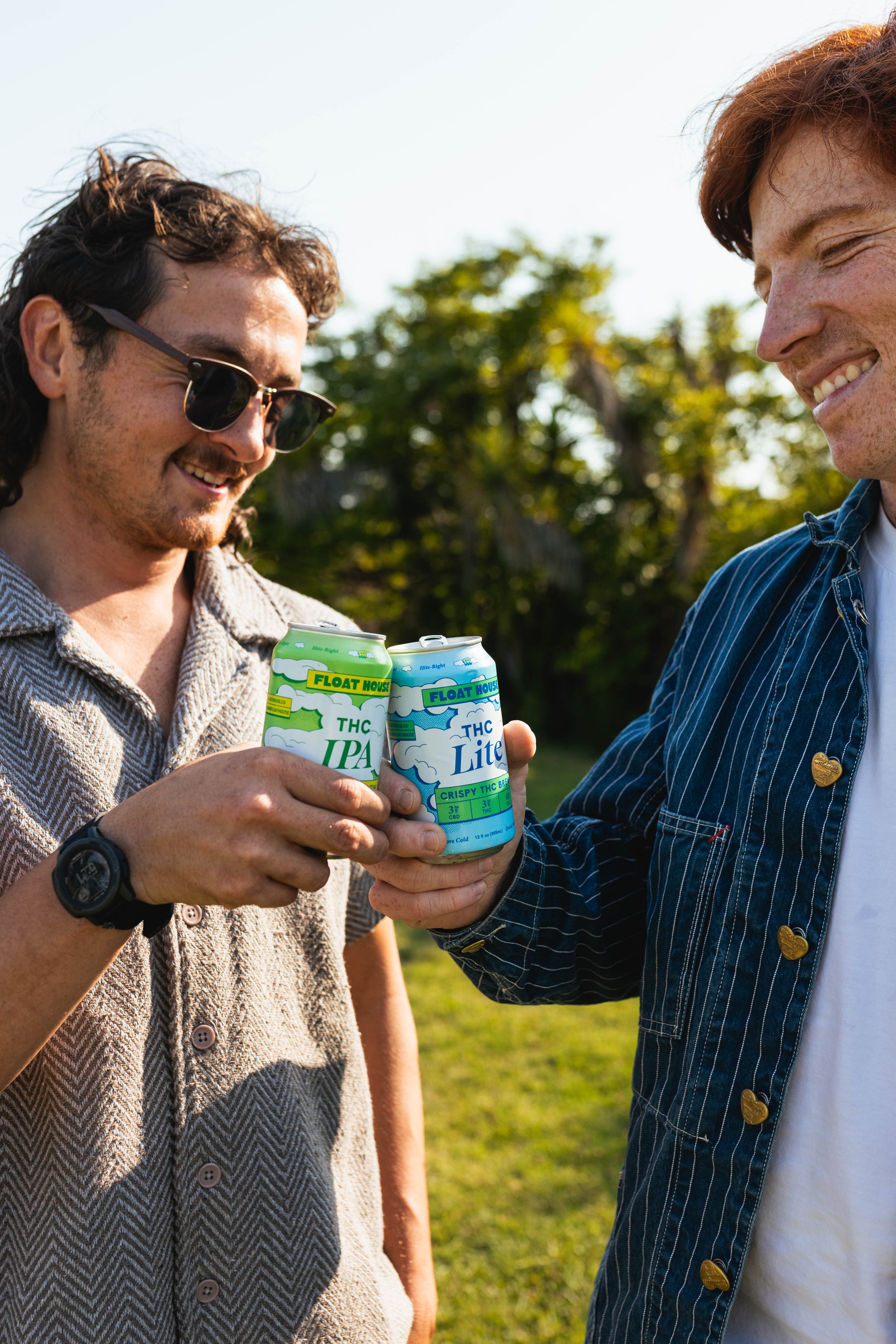Two people holding cans of Float House in a field